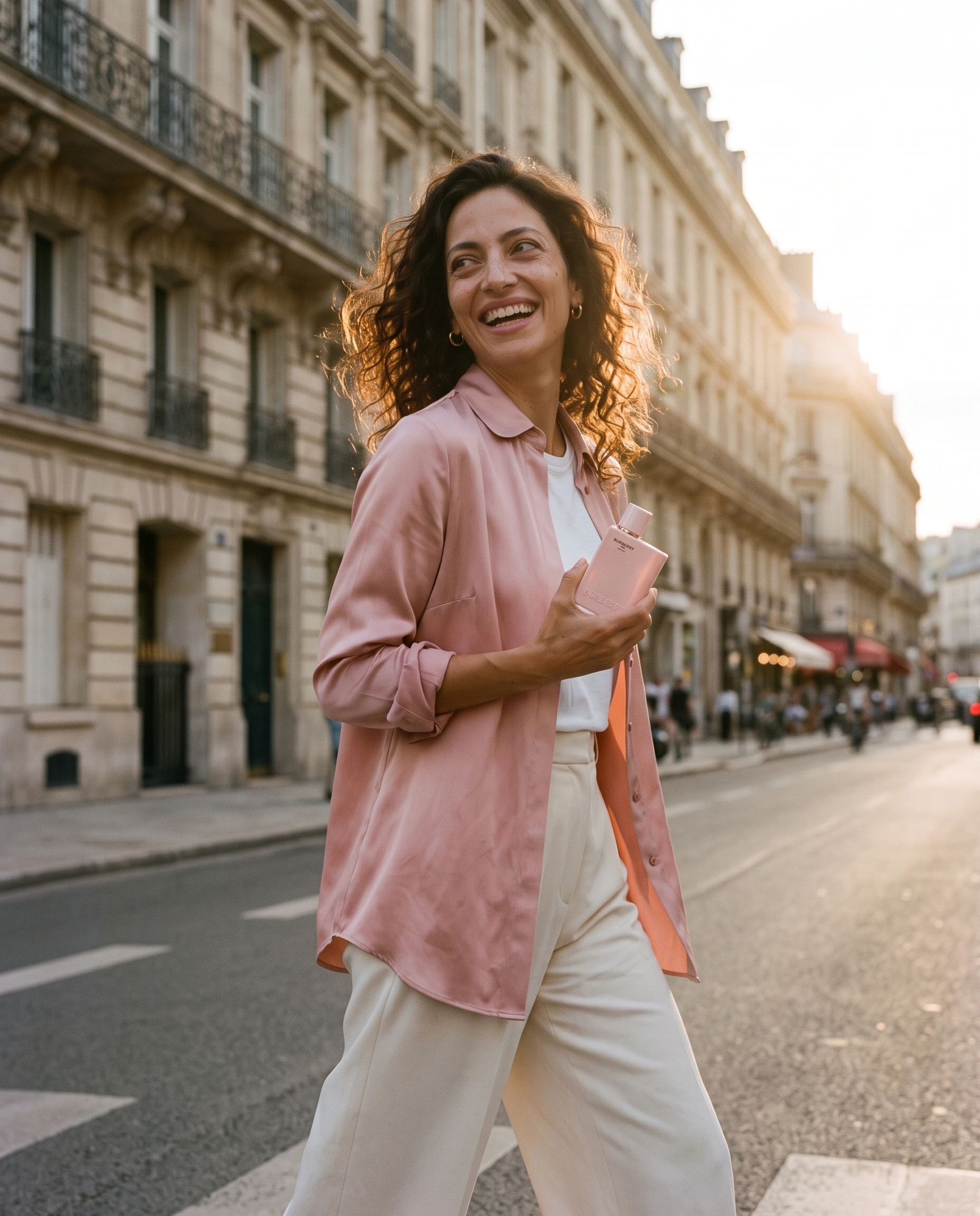 Femme riant dans une rue de Paris avec le flacon Burberry Her Parfum